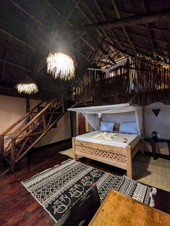 Le lit sous moustiquaire et l'escalier intérieur qui dessert la mezzanine