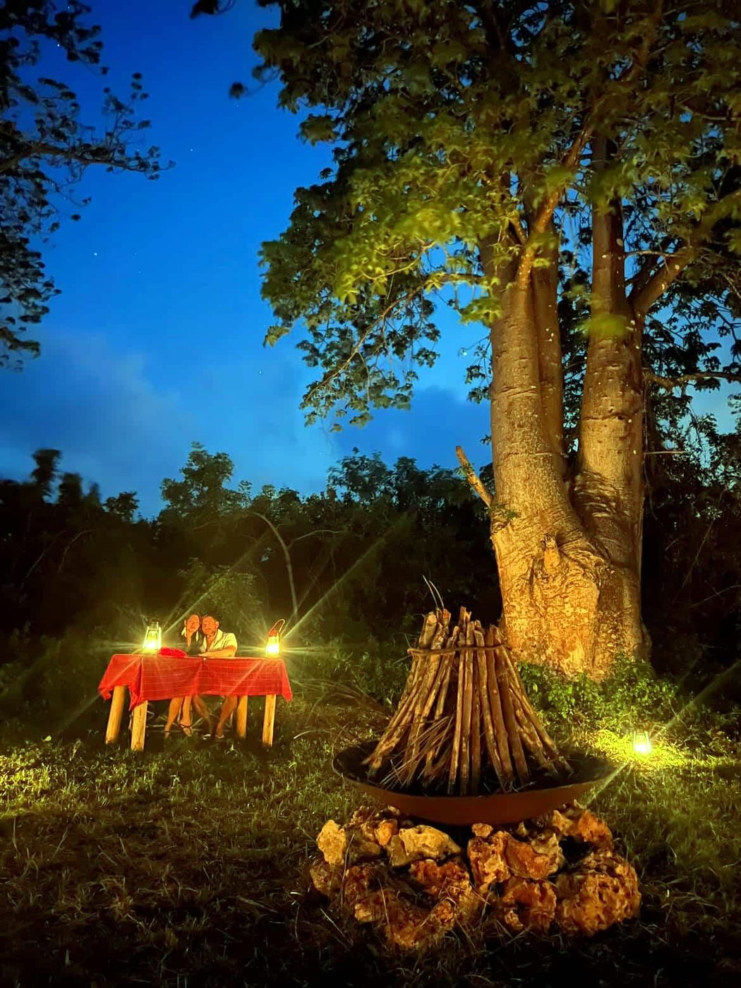 La table dressée pour deux au pied du baobab, à la tombée de la nuit